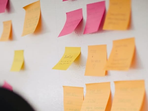 photo behind a person showing a whiteboard with post-it notes on